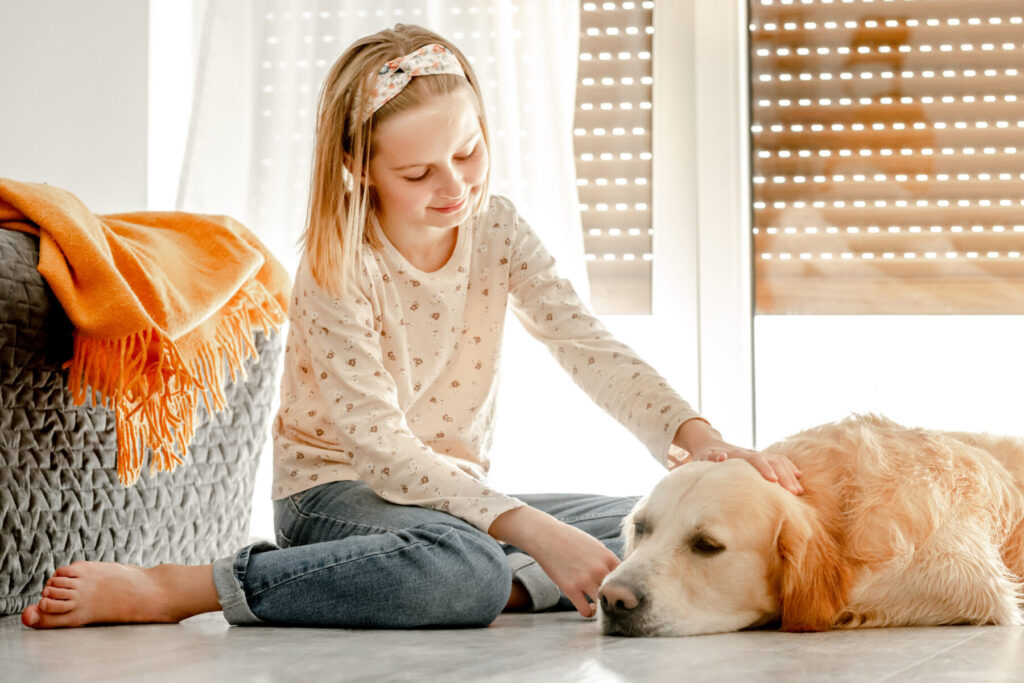 Girl with golden retriever dog on tile floor